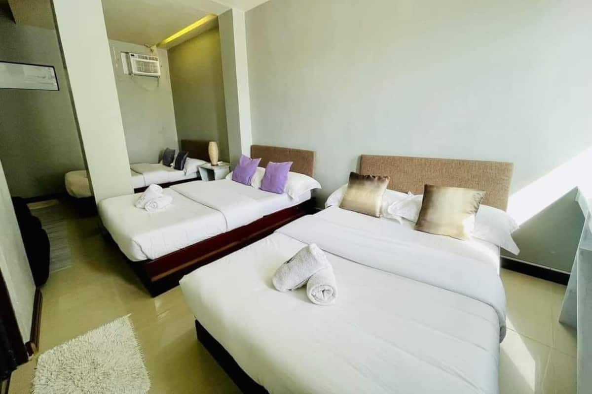 A hotel room with two beds, a large mirror, and a white rug.