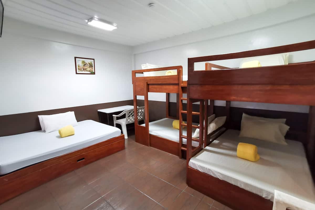 A room with bunk beds, a desk, and a chair.