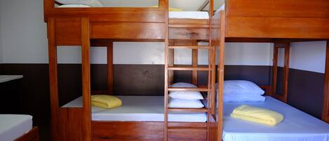 Ein Zimmer mit zwei Holzbettgestellen, jeweils ausgestattet mit Matratze und Kissen, verbunden durch eine Leiter.