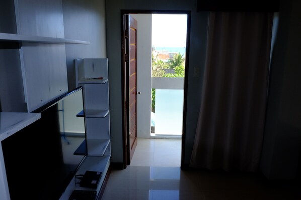 A room with a kitchenette, a door leading to a balcony with a view of the sea, and a sliding glass door. - Pacific Waves Inn Annex (Baler)