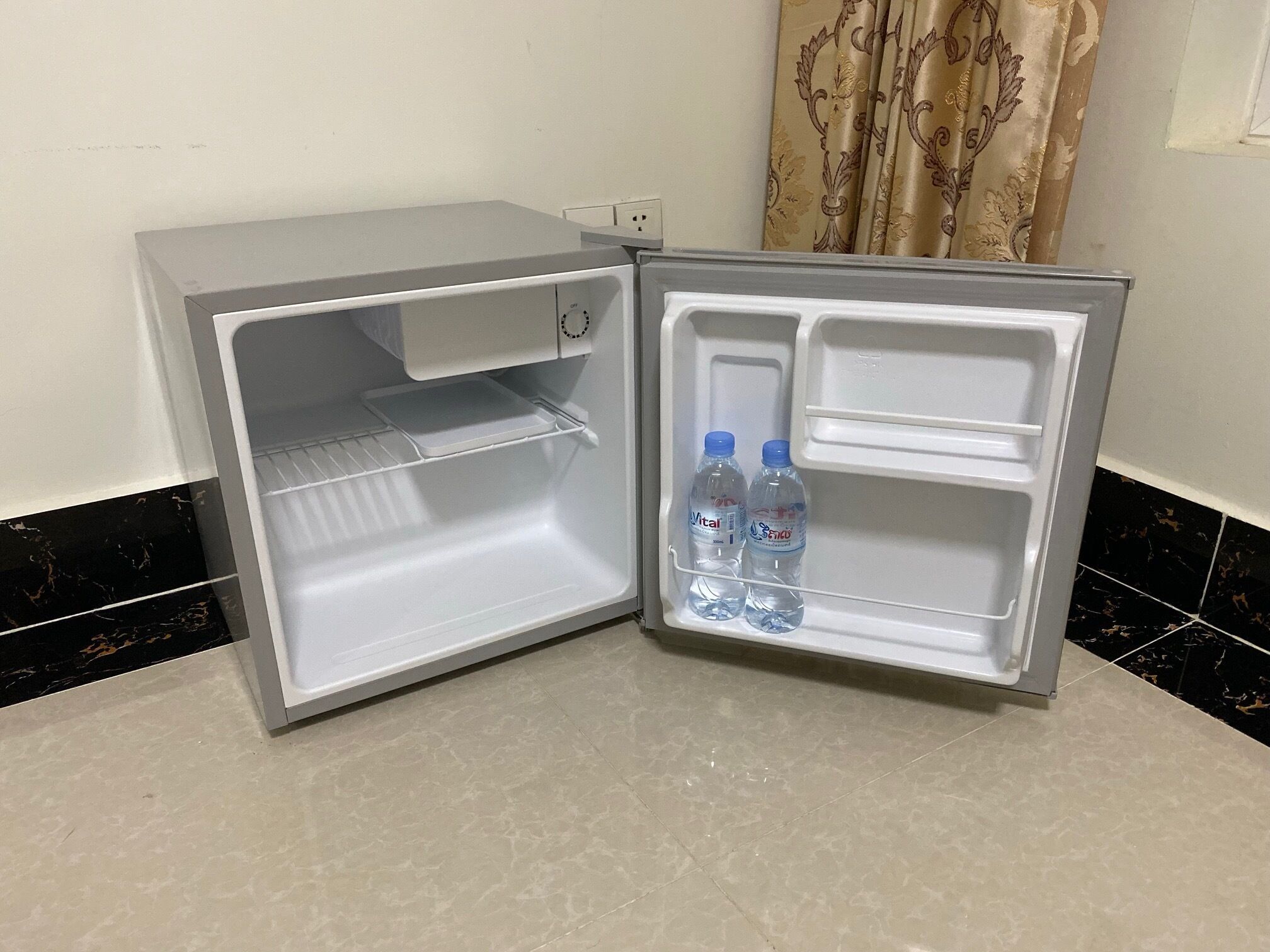 Ein kleiner, offener Kühlschrank mit zwei Wasserflaschen auf der Türablage.