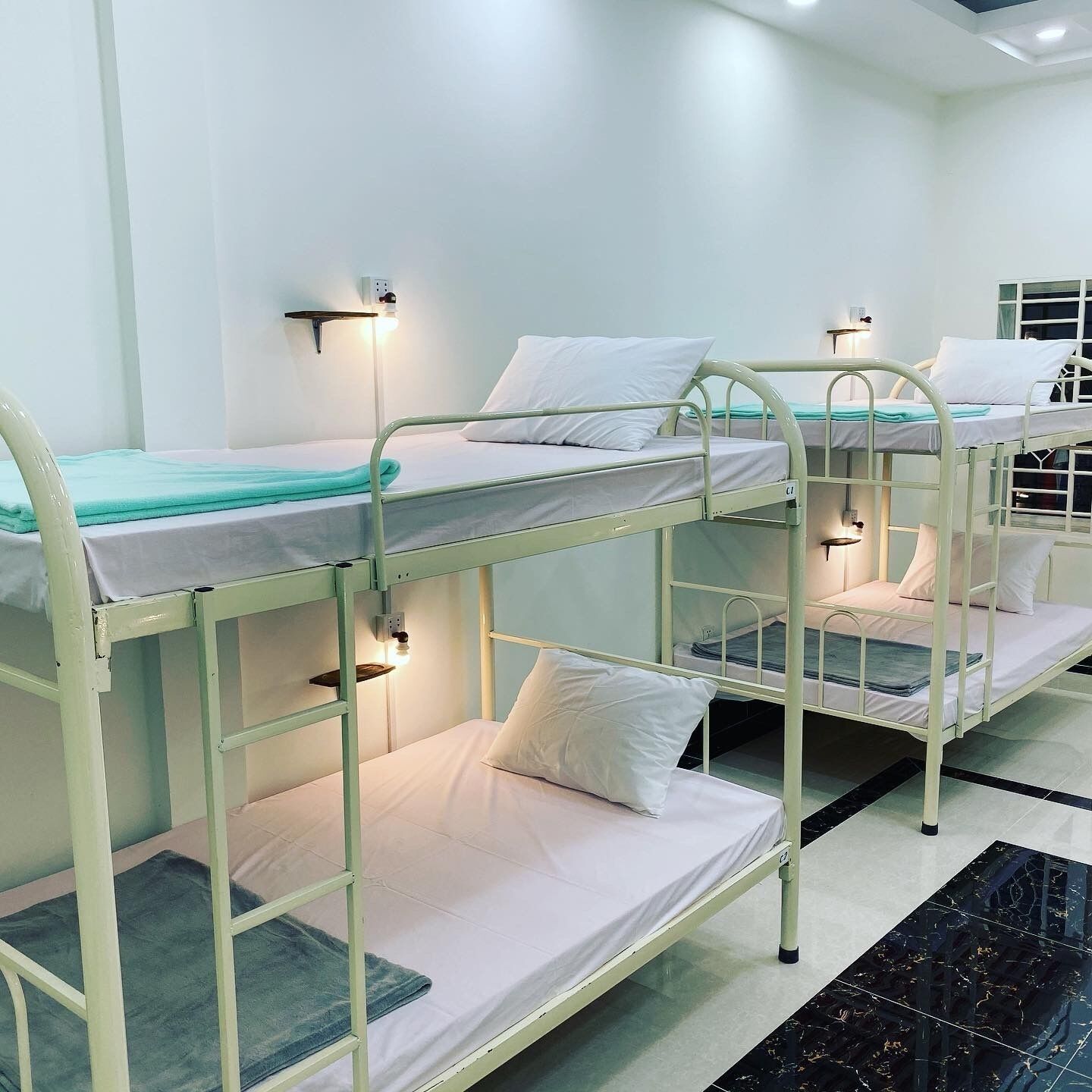 Habitación tipo dormitorio con literas, cada una con almohada y manta.