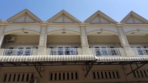 Un edificio de varios pisos con una fachada simétrica, que presenta un balcón central con barandillas ornamentadas y un techo a dos aguas.
