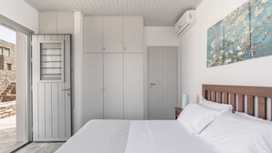 A bedroom with a large bed, white wardrobe, and a painting on the wall. - Villa Bianca Tzia (Kea)