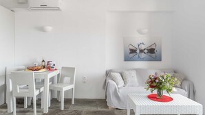 A modern living room with a dining area, a sofa, and a coffee table with a vase of flowers. - Villa Bianca Tzia (Kea)