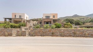 A modern two-story house with a stone facade, a flat roof, and a view of a hilly landscape. - Villa Bianca Tzia (Kea)