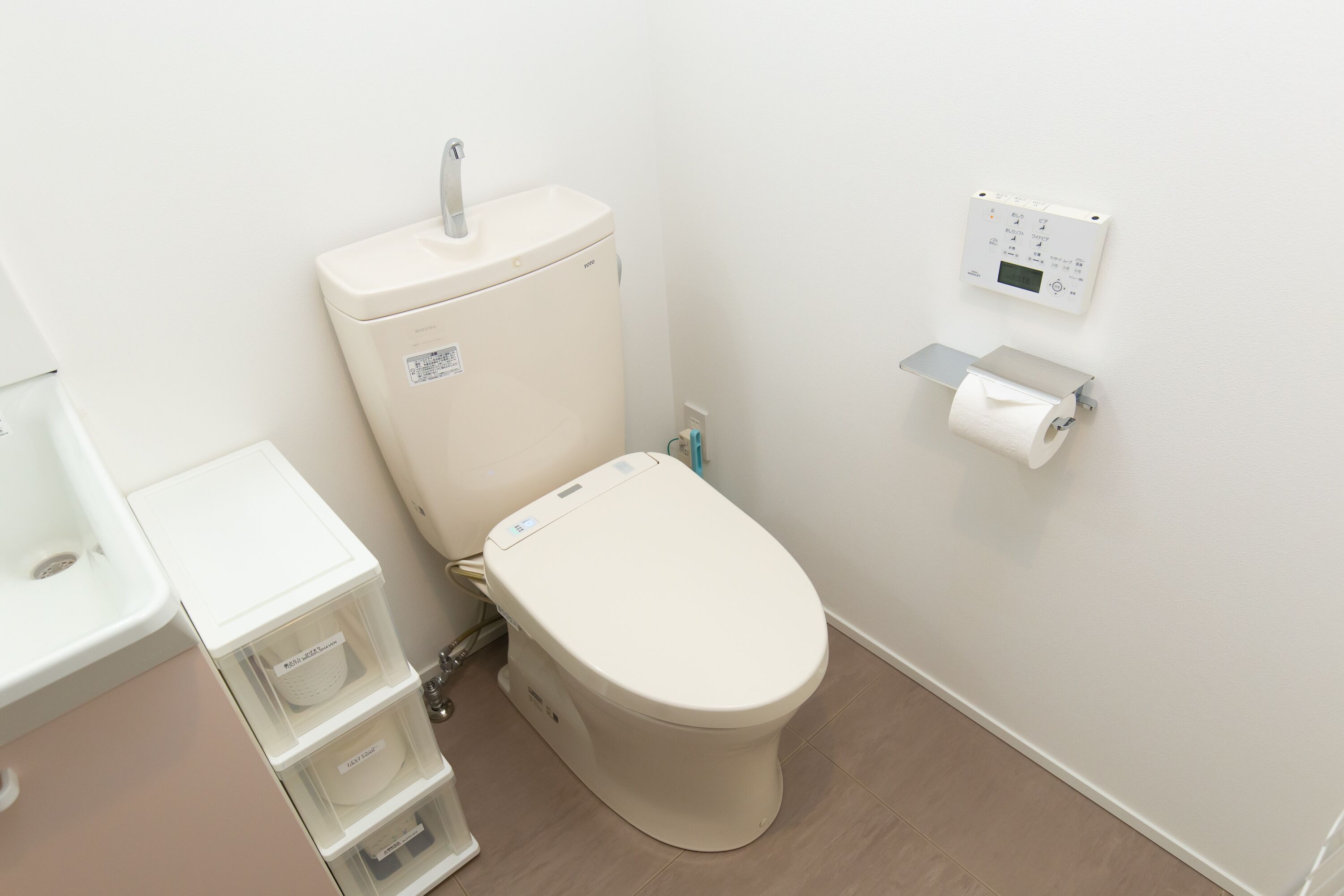 A modern bathroom with a toilet, a sink, and storage units.
