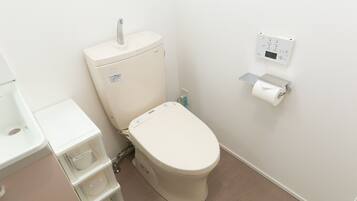 A modern bathroom with a toilet, a sink, and storage units.
