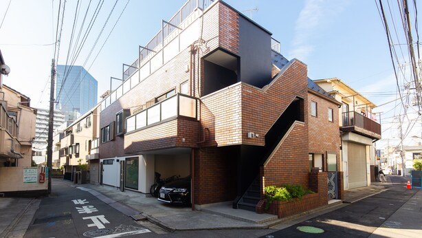 A modern two-story building with a brick facade, a garage, and a visible staircase leading to the upper floor. - Cross Bridge Ikebukuro (Tokyo)
