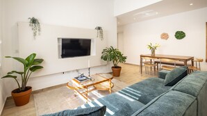Una sala de estar moderna con un sofá, una mesa de centro, un televisor montado en la pared y plantas en macetas.