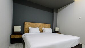 A modern bedroom with a large bed, wooden headboard, white bedding, and bedside tables with lamps. - TriDD 01 Sriwijaya Hotel (Mataram)