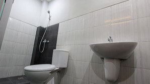 A bathroom with a toilet, a wall-mounted sink, and a shower. - TriDD 01 Sriwijaya Hotel (Mataram)