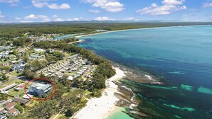 Vista aérea de una zona costera con un barrio residencial, una playa y aguas azul cristalino.