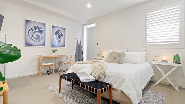 Un dormitorio moderno con una cama grande, un escritorio y dos cuadros en la pared.