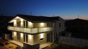 Een modern huis met twee verdiepingen, een balkon en meerdere ramen.