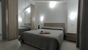 Een moderne hotelkamer met een groot bed, een nachtkastje, een spiegel en een dienblad met een kop en schotel.