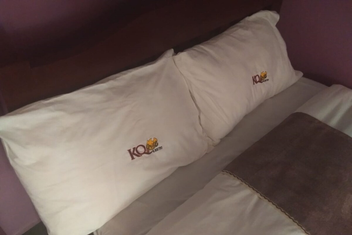 A bed with two pillows, each featuring a logo.