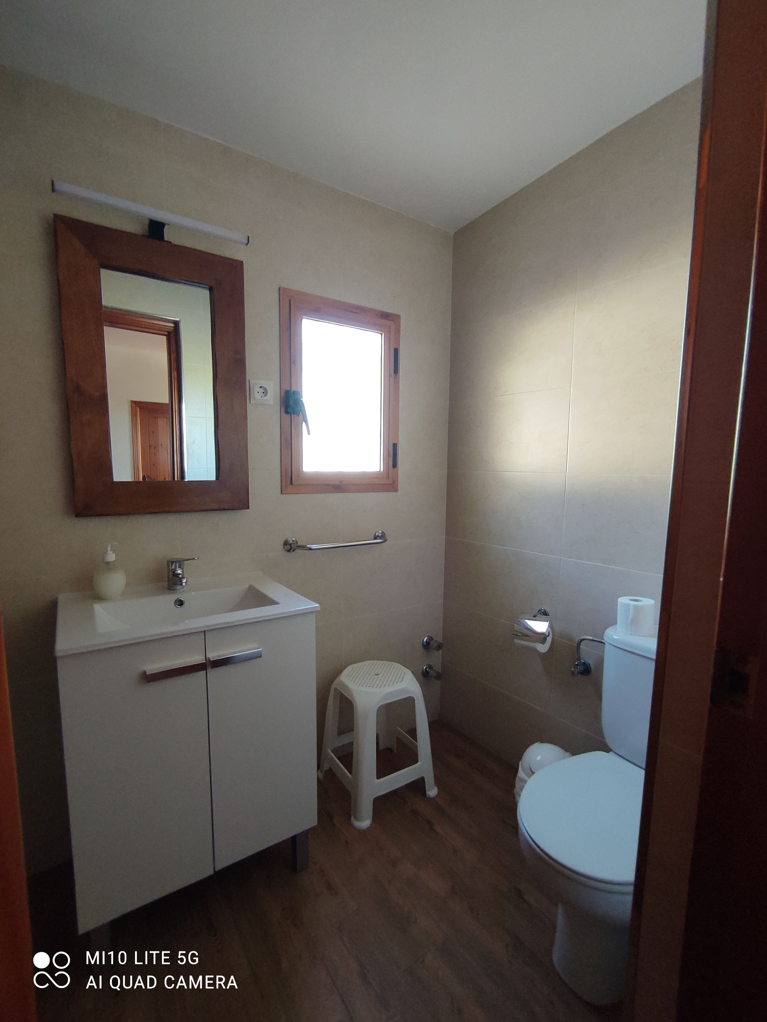 A bathroom with a white sink, mirror, and toilet.