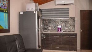 A modern kitchen with dark cabinets, a tiled backsplash, and a gas stove. - Hot tub 1 bedroom AC Security 2 blocks from lleras (Medellin)