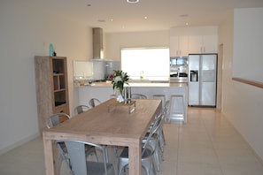 A modern kitchen with a wooden dining table, metal chairs, and a built-in oven. - Waterview- Stoneleigh at Yarra (Yarrawonga)