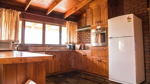 A kitchen with wooden cabinets, a white refrigerator, a microwave, and a toaster. - Water's Edge Bundalong (Bundalong)