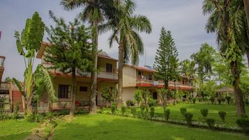 A two-story building with a balcony, surrounded by lush greenery and palm trees.
