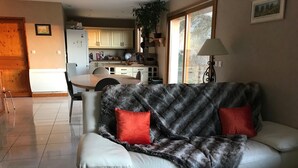 A living room with a white leather sofa, two red cushions, a fur throw, and a lamp. - Detached house on large plot of land near Jura and wine route (Vielverge)