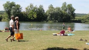 A lakeside park with people walking, sitting on the grass, and swimming. - Detached house on large plot of land near Jura and wine route (Vielverge)