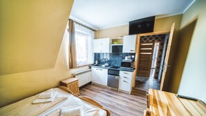 A compact room with a bed, a wooden table, a kitchenette, and a bathroom. - Pokoje i Apartamenty Nad Potokiem (Zakopane)