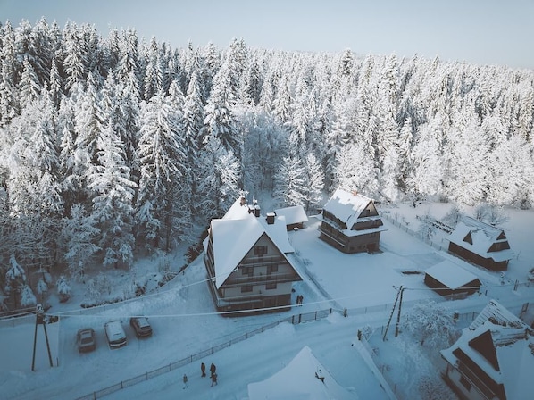 A snow-covered lodge with multiple cabins, surrounded by dense forest.