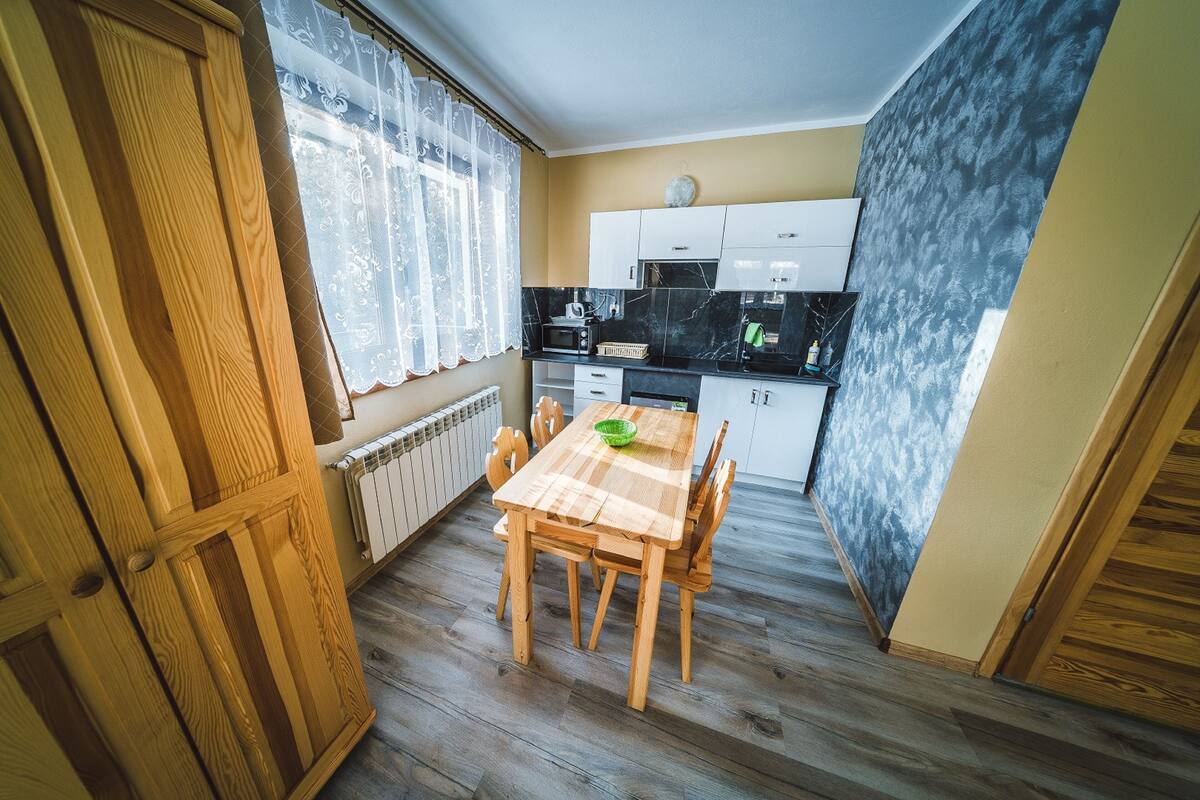 A compact kitchen with a wooden table and chairs, a microwave, and cabinets.