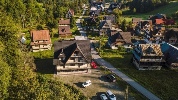 A residential area with houses, a parking lot, and a road. - Pokoje i Apartamenty Nad Potokiem (Zakopane)
