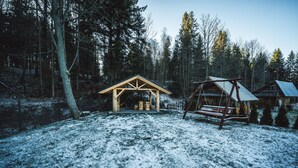 A wooden cabin with a snow-covered ground, surrounded by trees. - Pokoje i Apartamenty Nad Potokiem (Zakopane)
