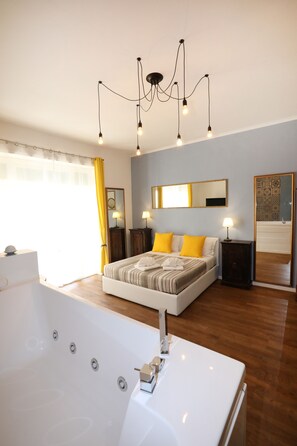 A modern bedroom with a large bed, a bathtub, and a chandelier. - Unique Luxury Apartment and Rooms (Rome)