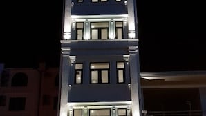 Exterior do Hotel An Phu, com uma placa iluminada em destaque, uma grande entrada em arco e um veículo estacionado em frente.