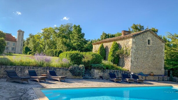 A swimming pool with lounge chairs, a stone building, and a large tree in the background. - Chateau les Estournels (Lendou-en-Quercy)