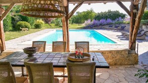 An outdoor dining area with wicker chairs and a table, overlooking a swimming pool and garden. - Chateau les Estournels (Lendou-en-Quercy)