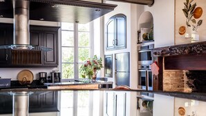 A modern kitchen with stainless steel appliances, a central island, and a view of the outdoors. - Chateau les Estournels (Lendou-en-Quercy)