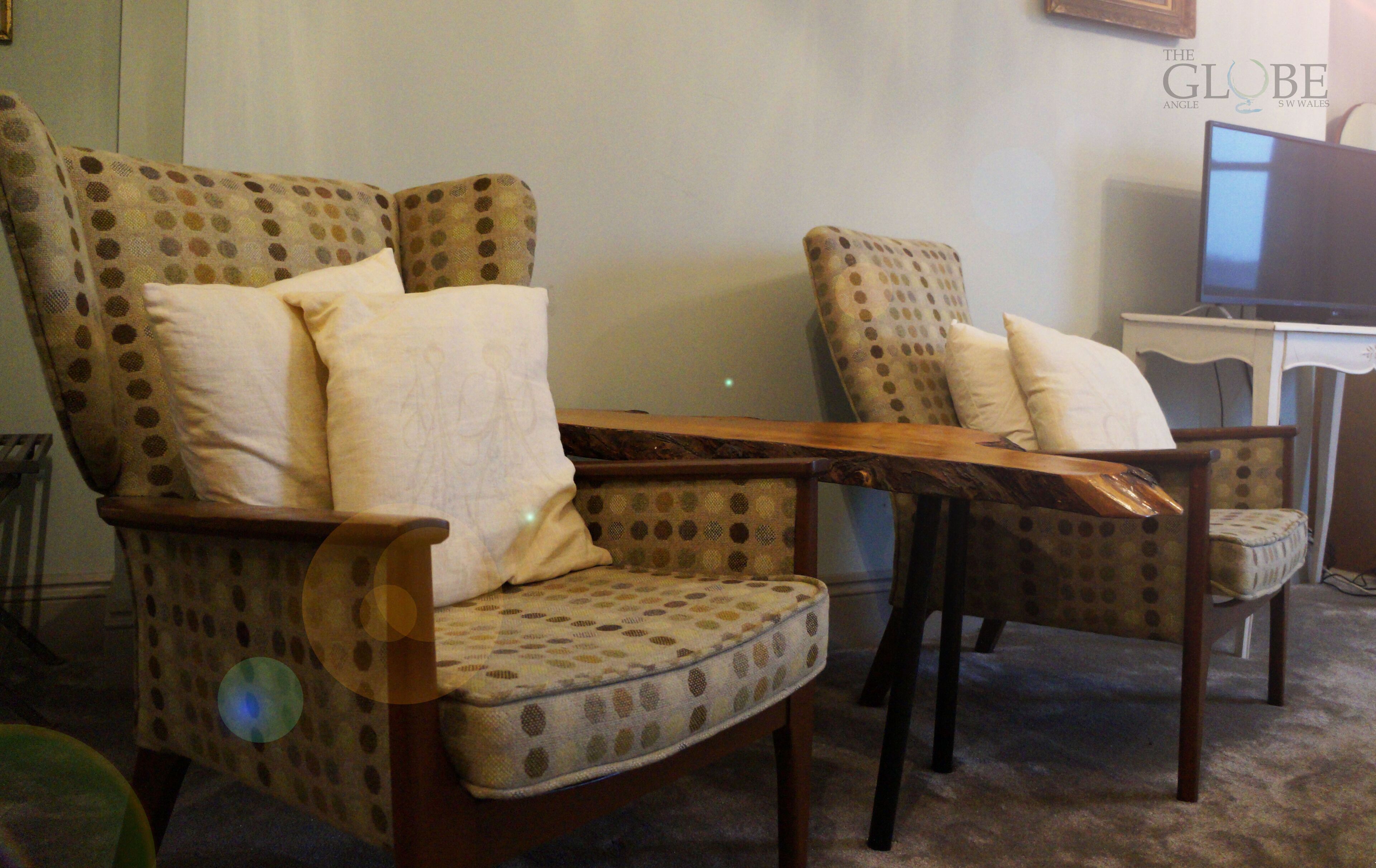 Two patterned armchairs with cushions, a wooden coffee table, and a television on a stand.