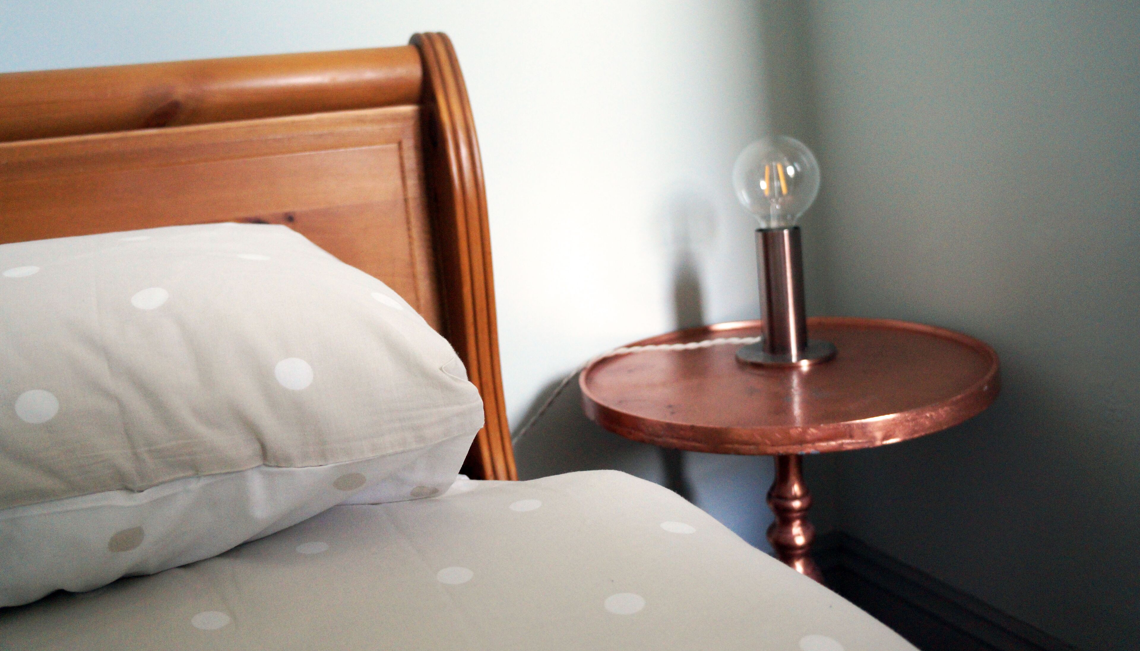 A bed with a wooden headboard and a white pillow with polka dots.