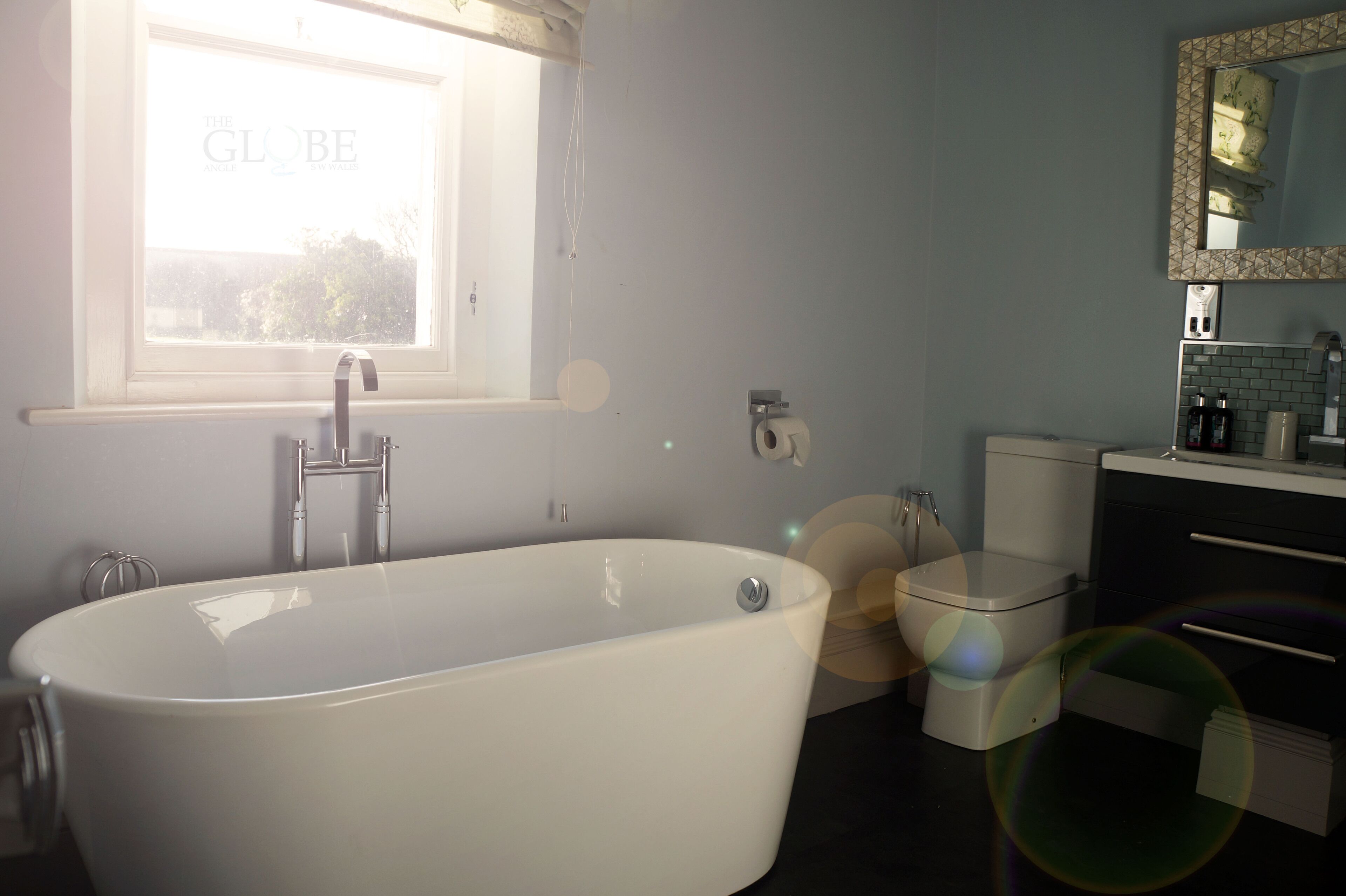 A bathroom with a freestanding bathtub, a toilet, a sink, and a mirror.