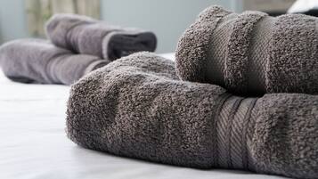 Neatly folded gray towels on a bed.