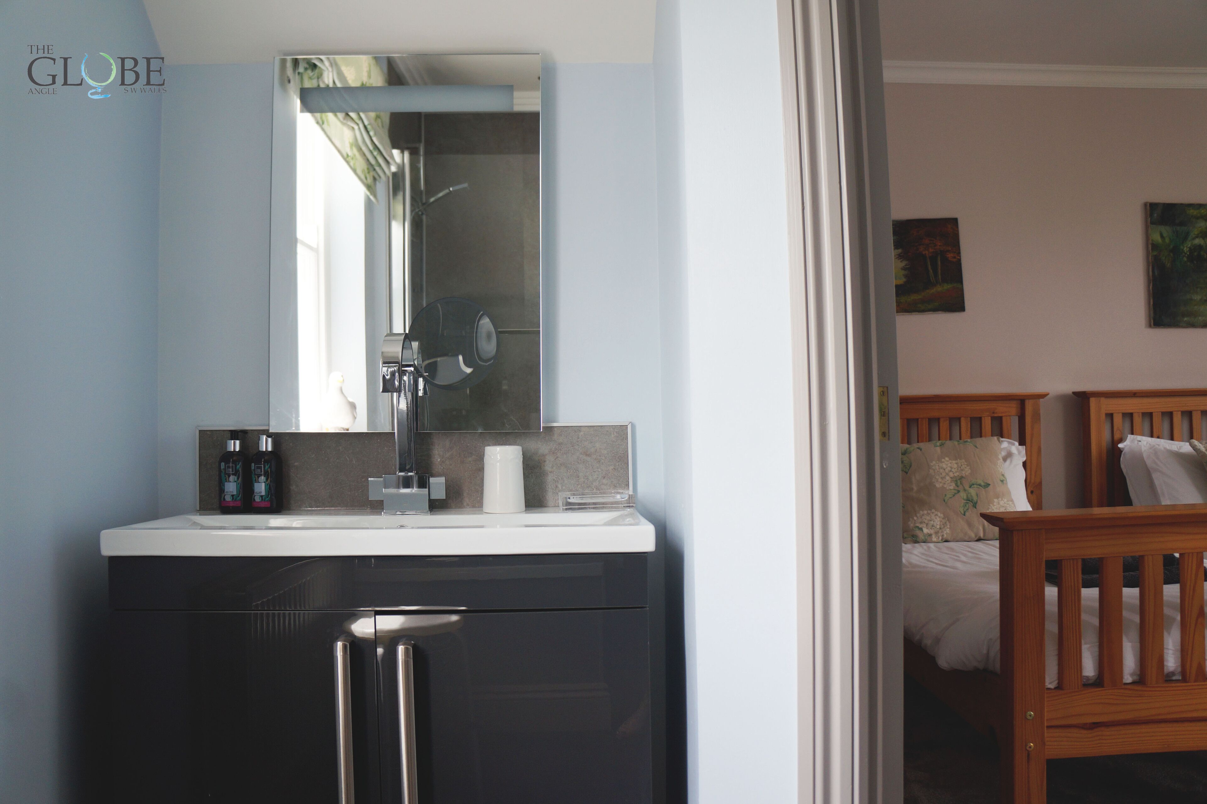 A modern bathroom with a sink, mirror, and shower.