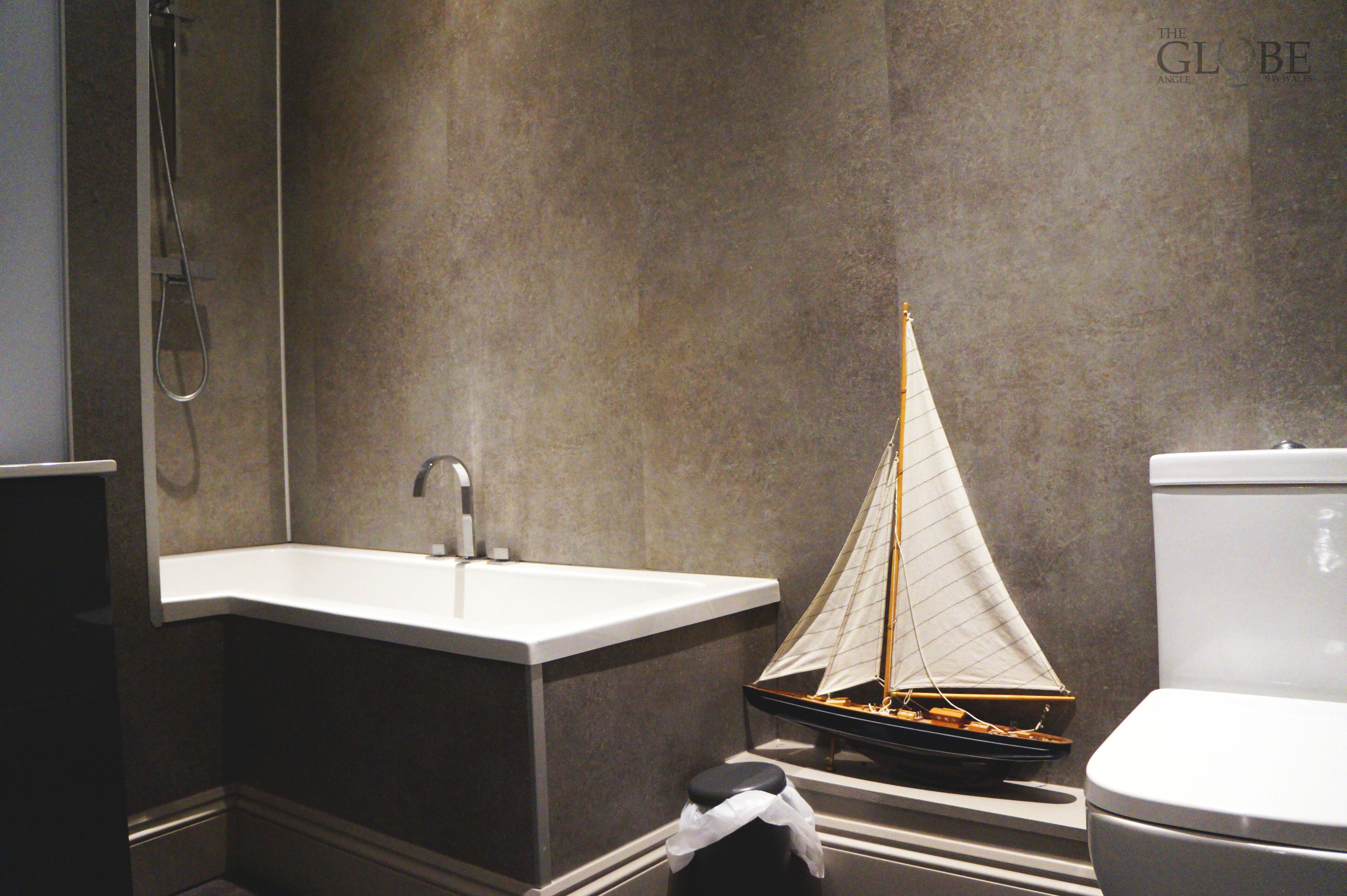 A bathroom with a white sink, a toilet, and a small sailboat model.