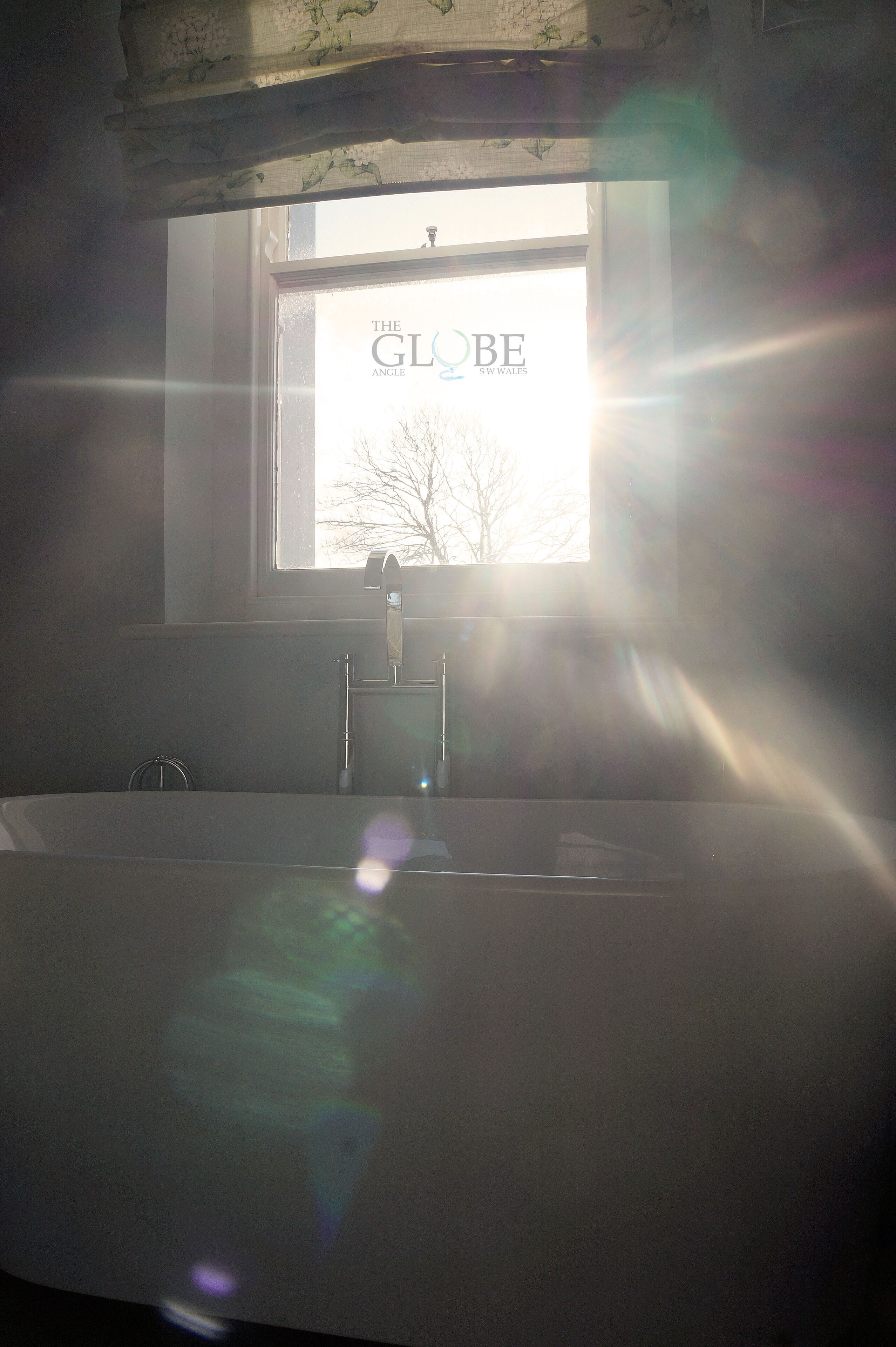 A bathroom with a window, a sink, and a mirror.