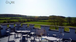 Eine Terrasse mit Sitzgelegenheiten und einem malerischen Ausblick auf sanfte Hügel.