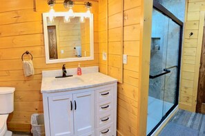 Un bagno con parete in legno, lavandino con specchio e porta doccia in vetro.