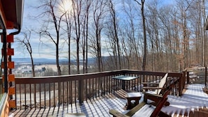 Une terrasse en bois offrant une vue sur une forêt et des collines lointaines.