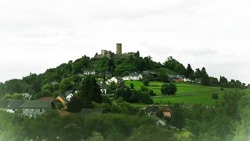 A hilltop village with a prominent tower, surrounded by lush greenery and houses.