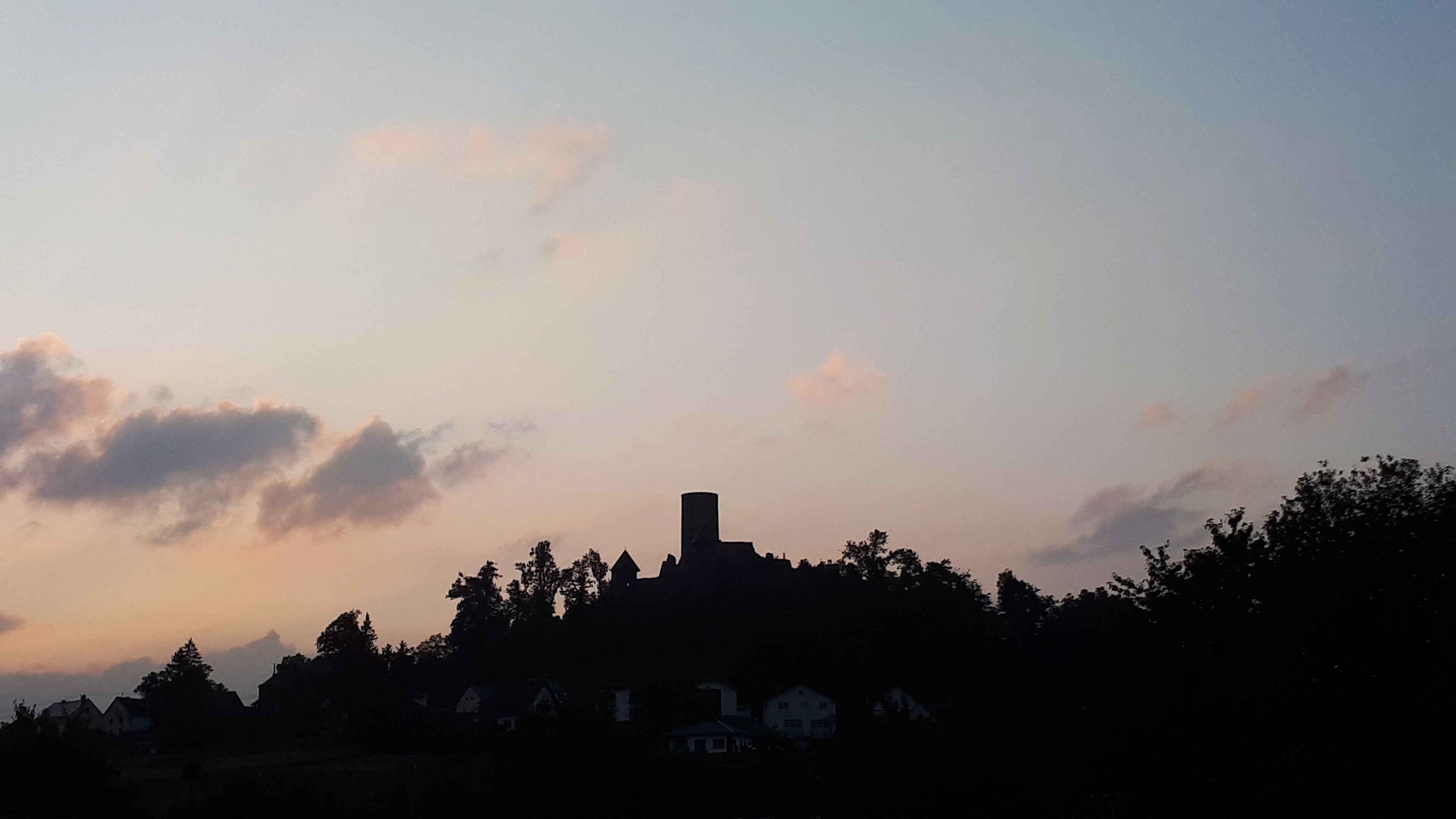 A silhouette of a building with a prominent tower against a twilight sky.